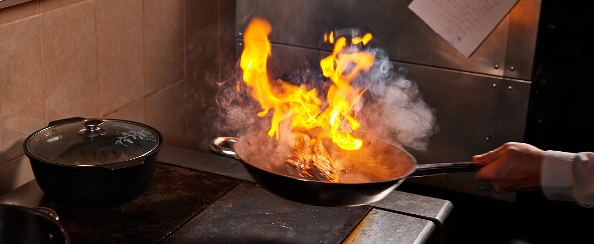Cooking wok catching fire on a stove representing a burn injury claim