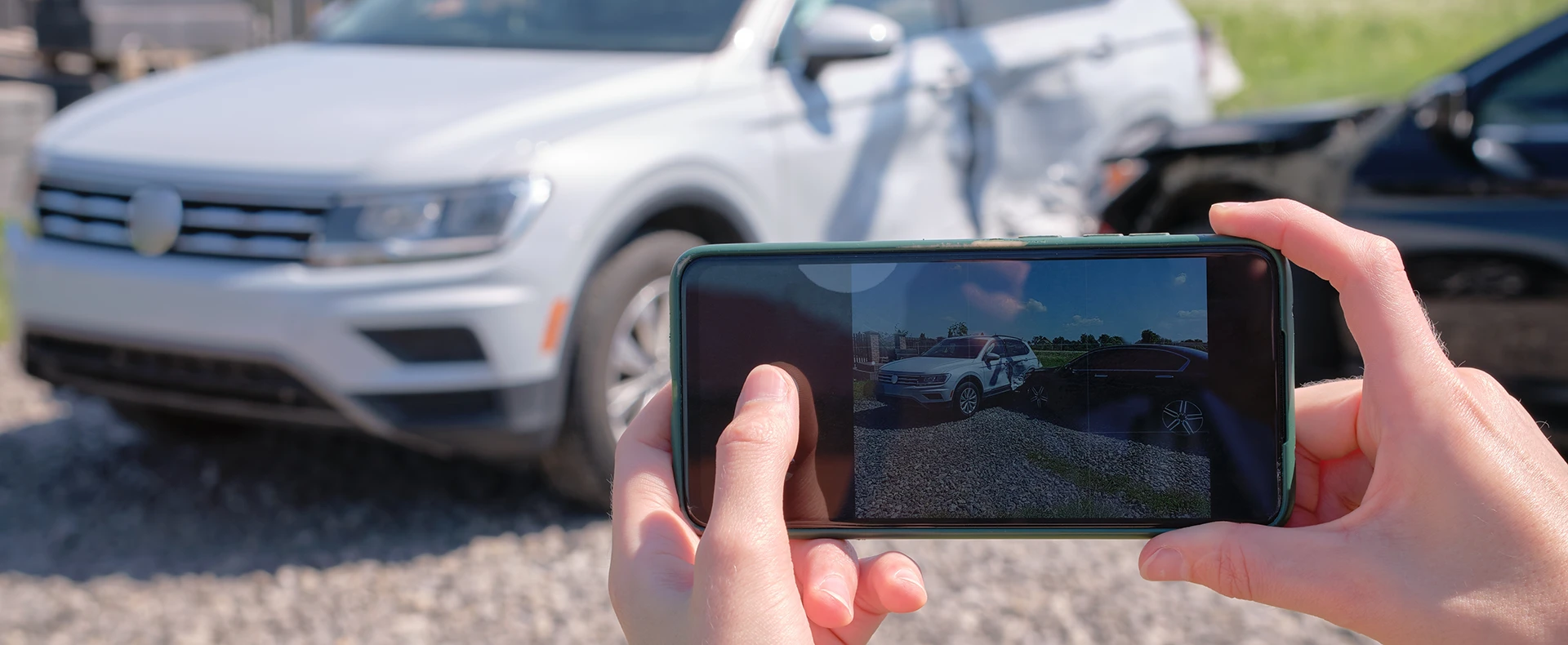 Hands taking a photo of a damaged car to preserve evidence after an accident