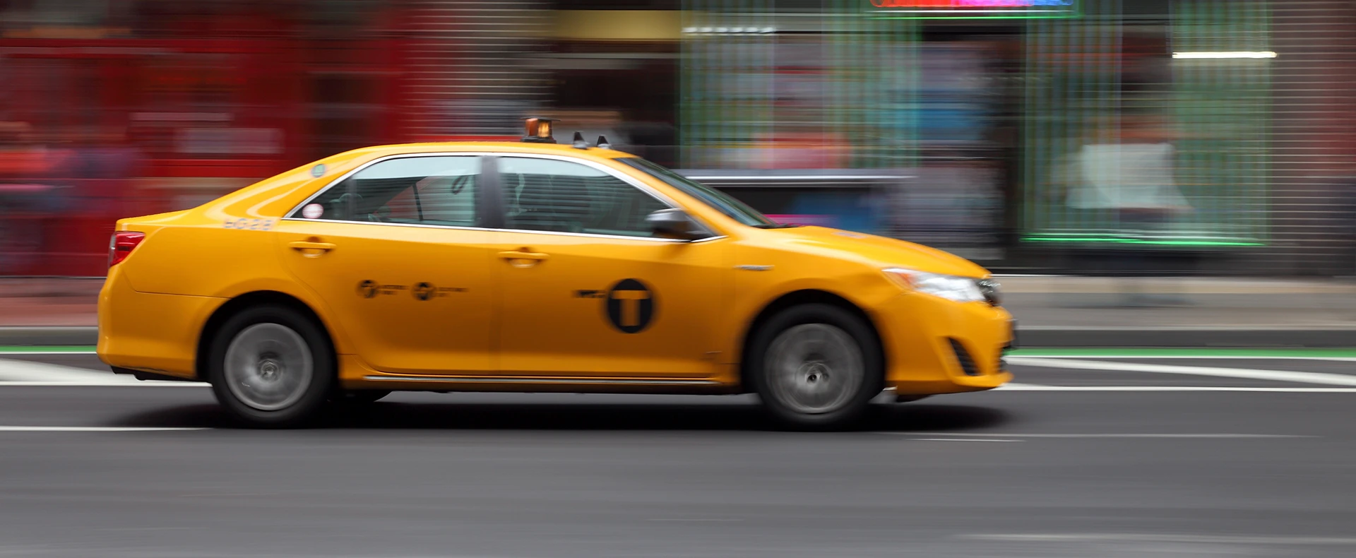 Yellow taxi cab driving fast along a city street representing a taxi accident claim